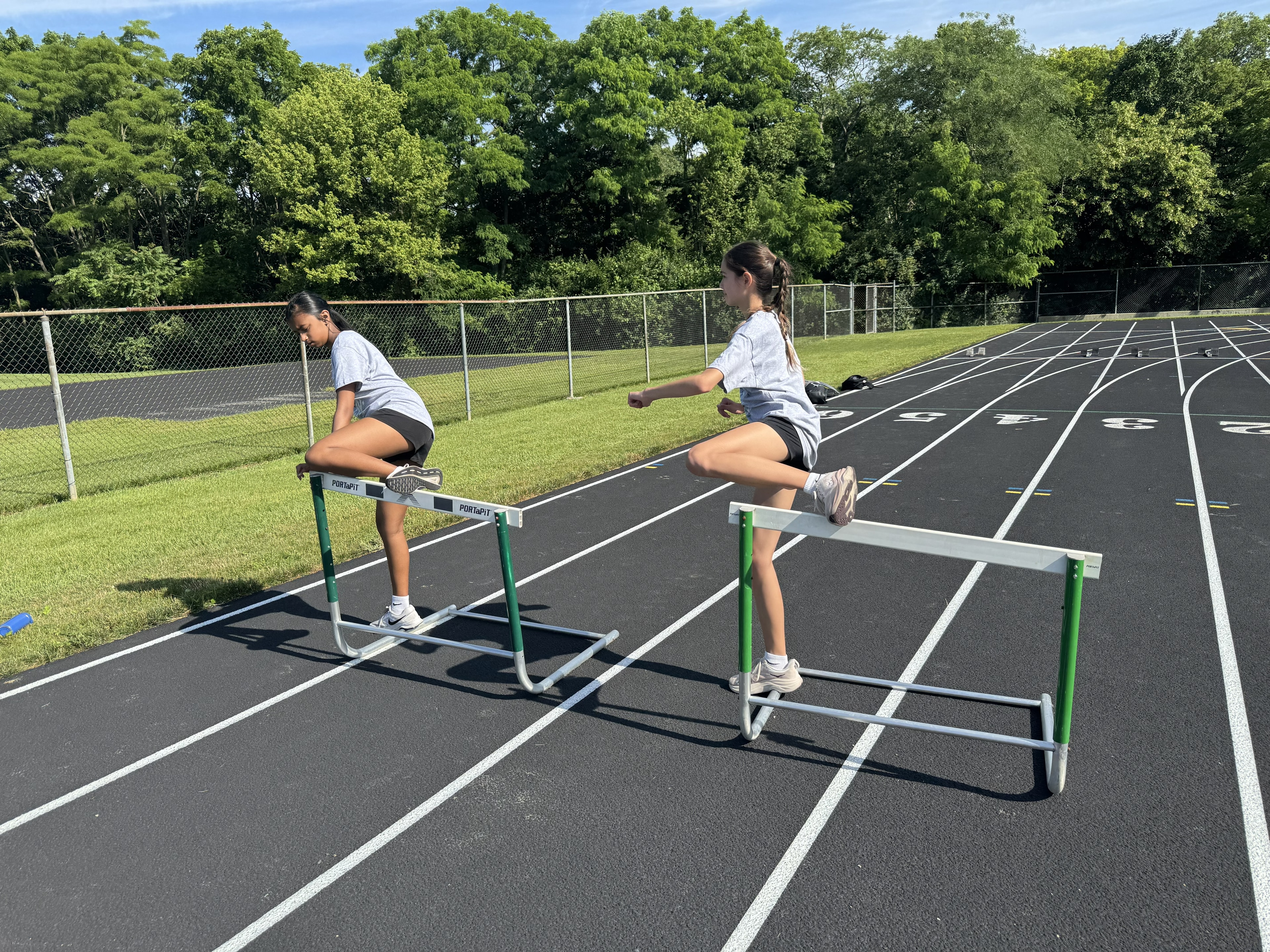 Two girls practicing hurdle drills on the Scioto track