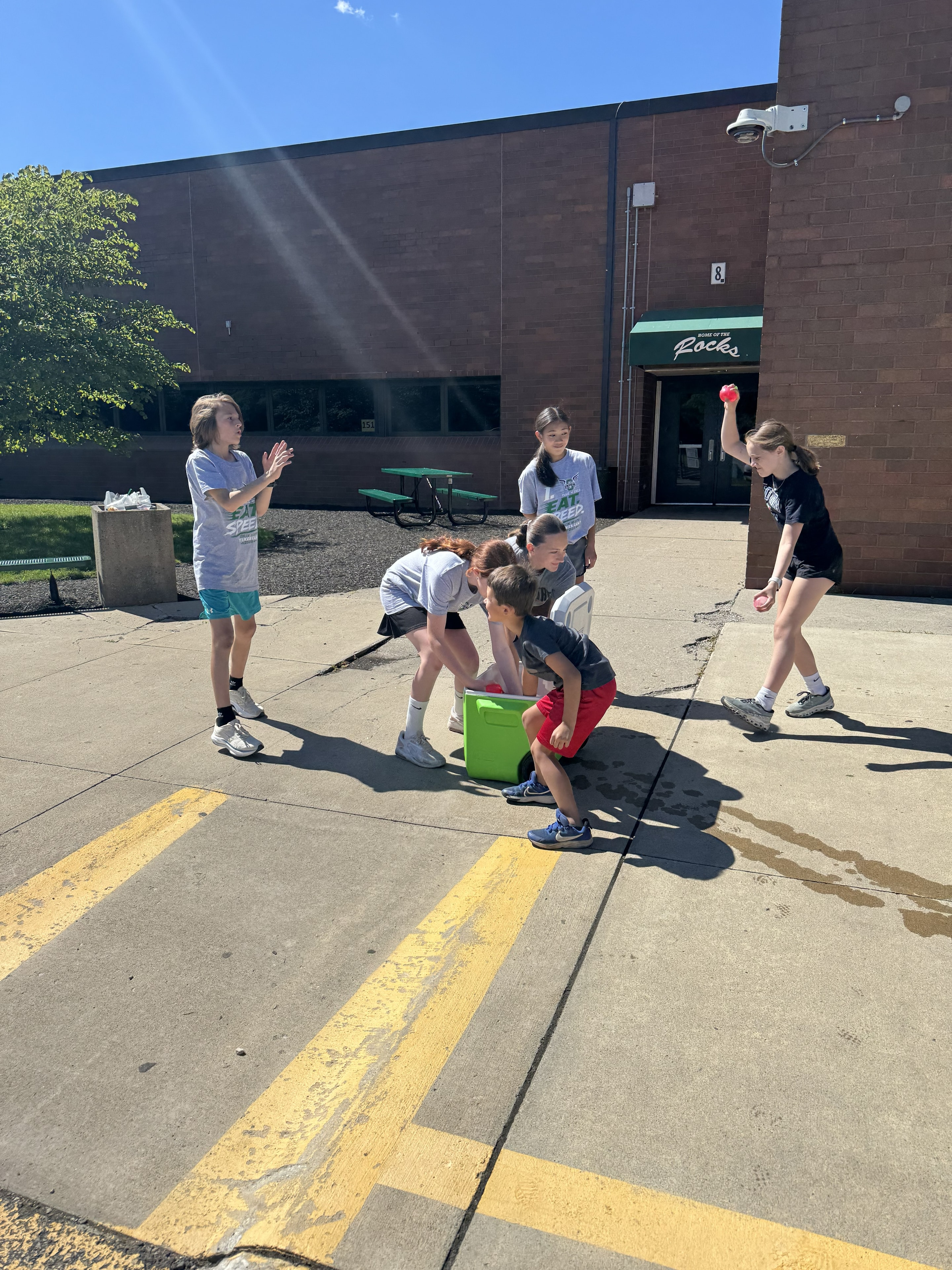 Campers playing a water balloon game outside the school