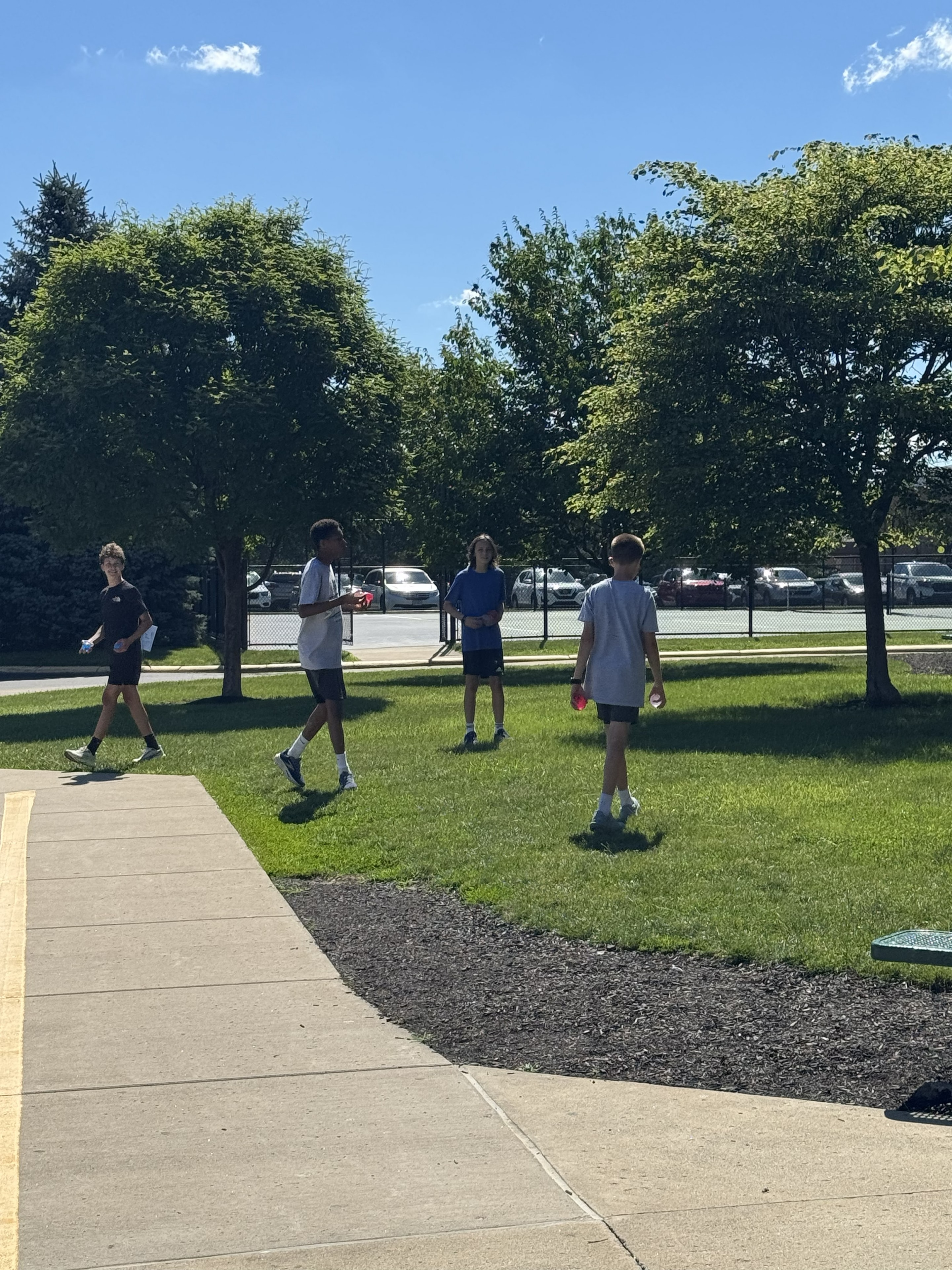 Boys playing catch with water balloons on the school lawn