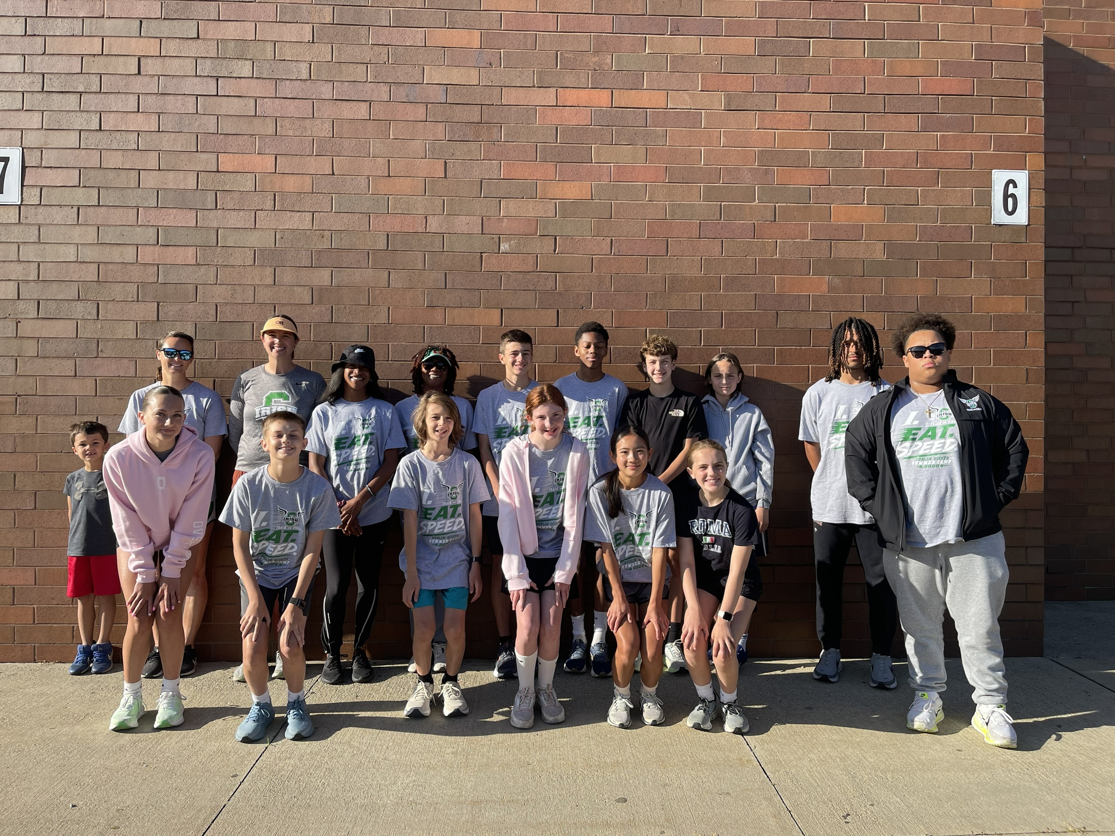 Full summer camp group photo against the brick wall