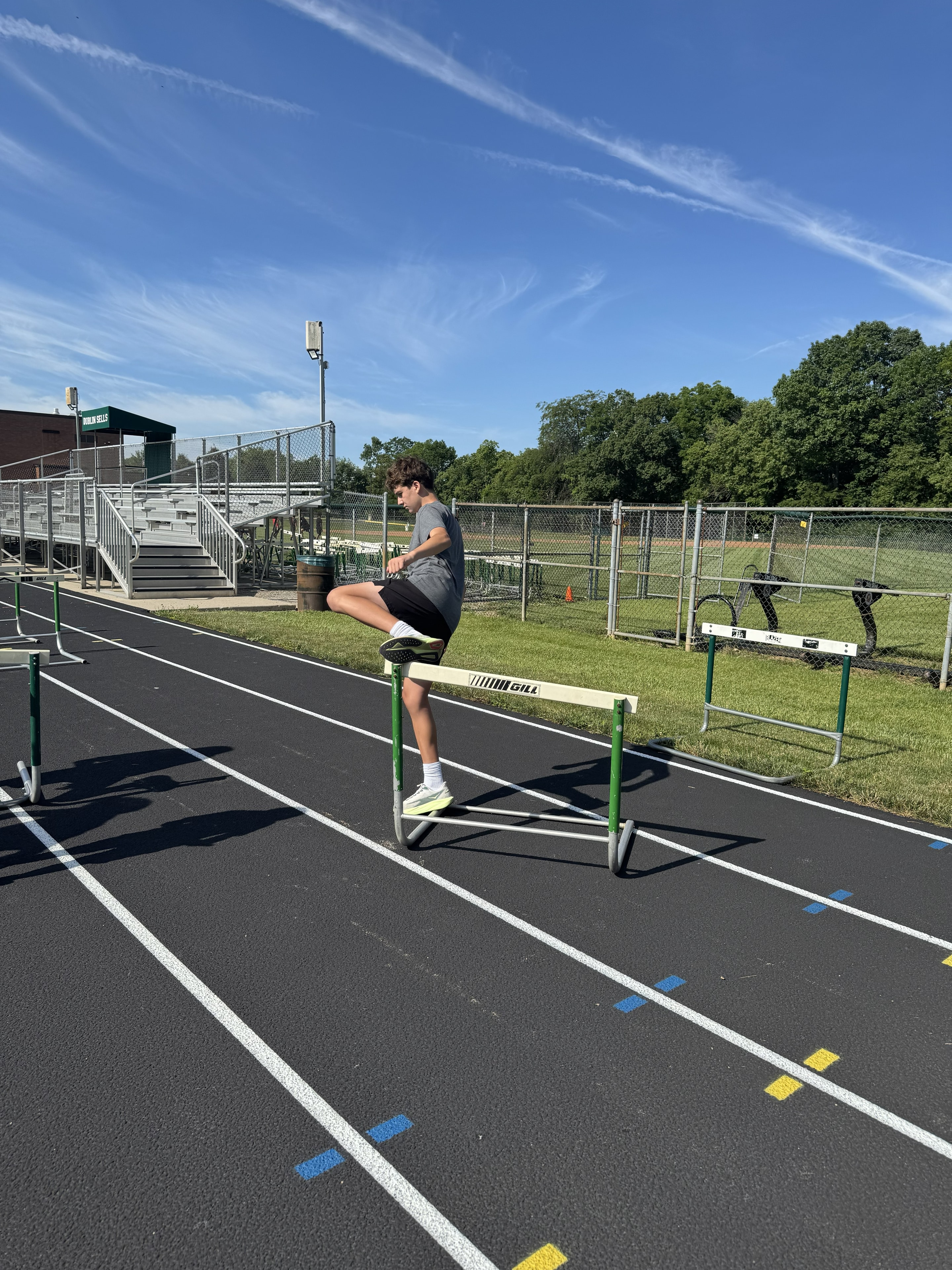 Boy clearing a hurdle on the track at summer camp