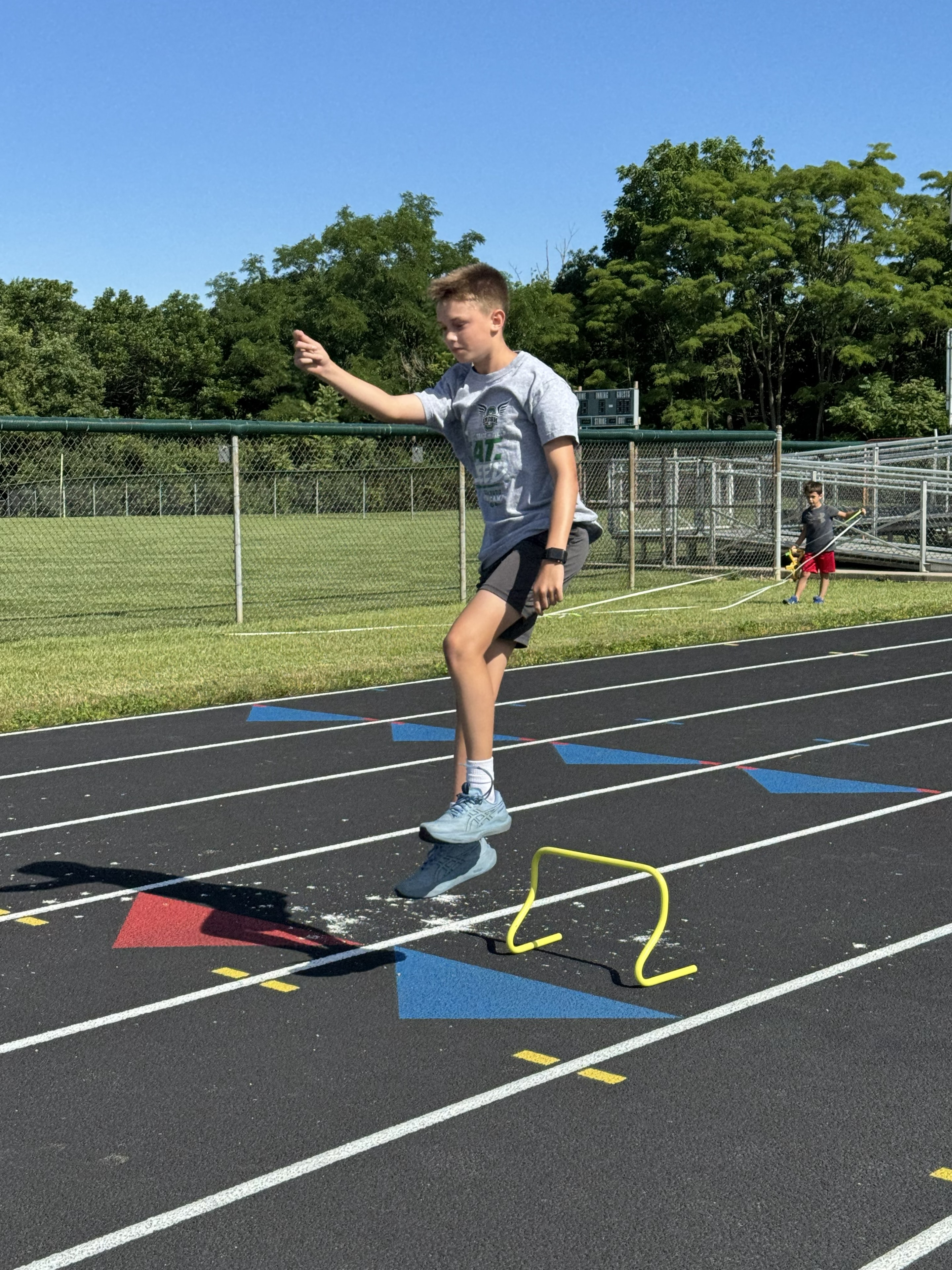 Camper bounding over mini hurdles on the track