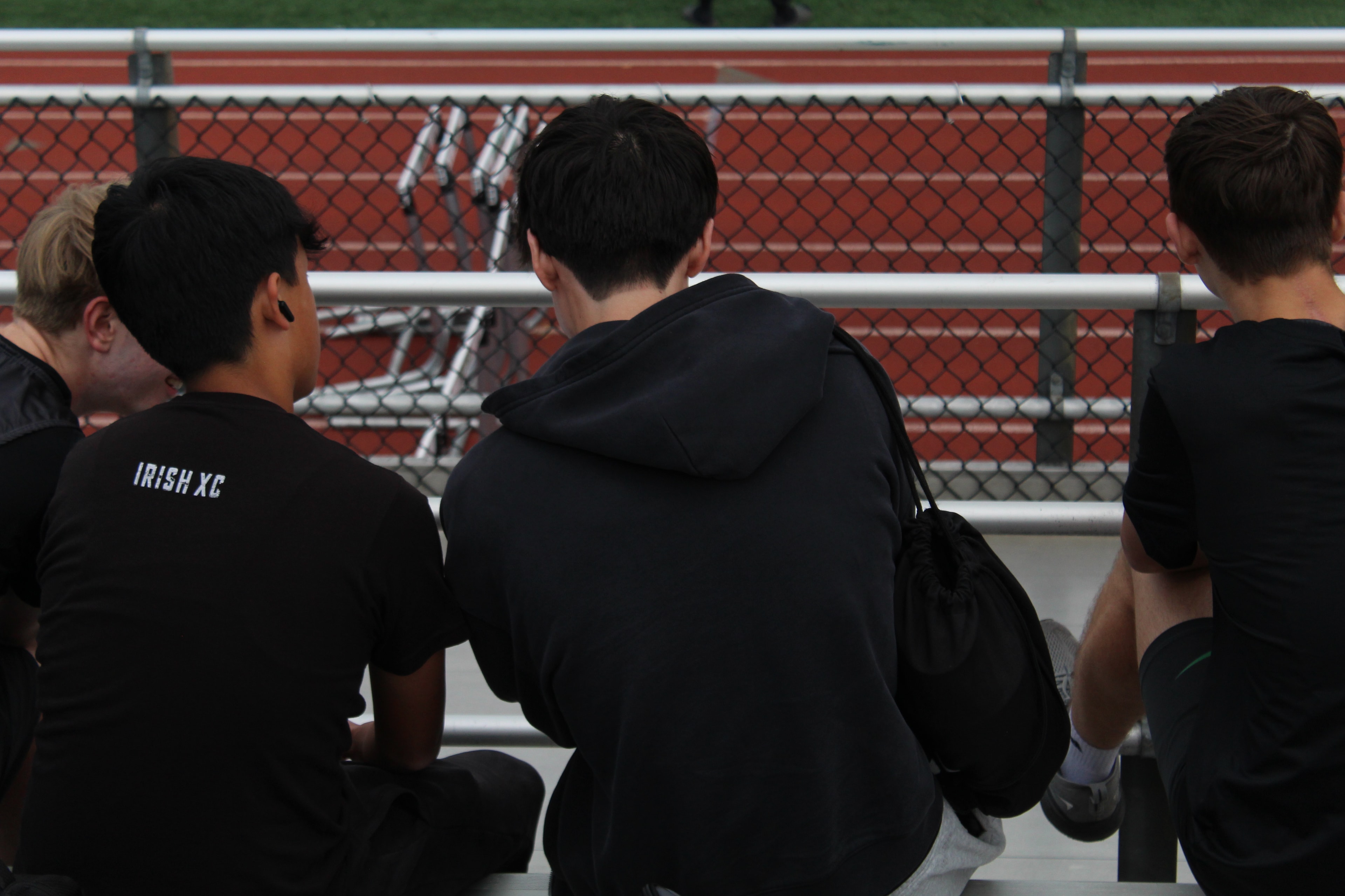 Irish XC boys watching the action from the bleachers at a meet