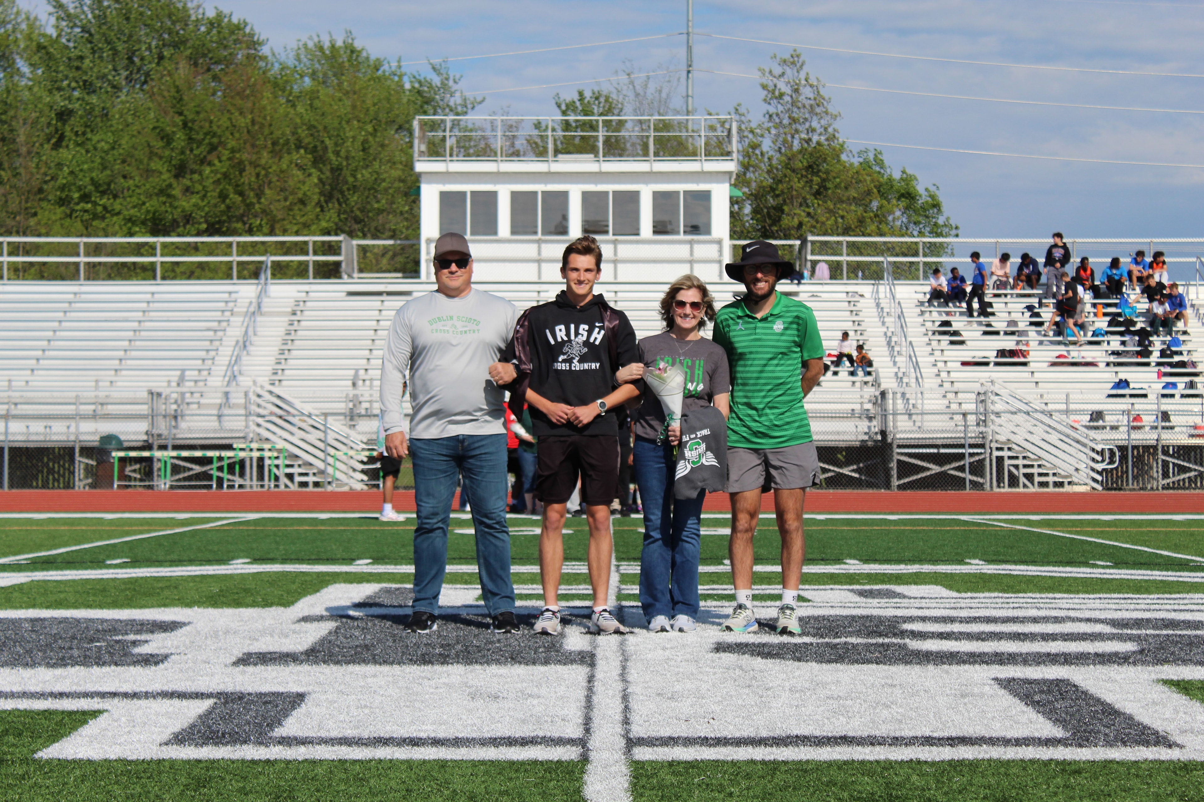 Senior in Irish Cross Country hoodie with family on the field