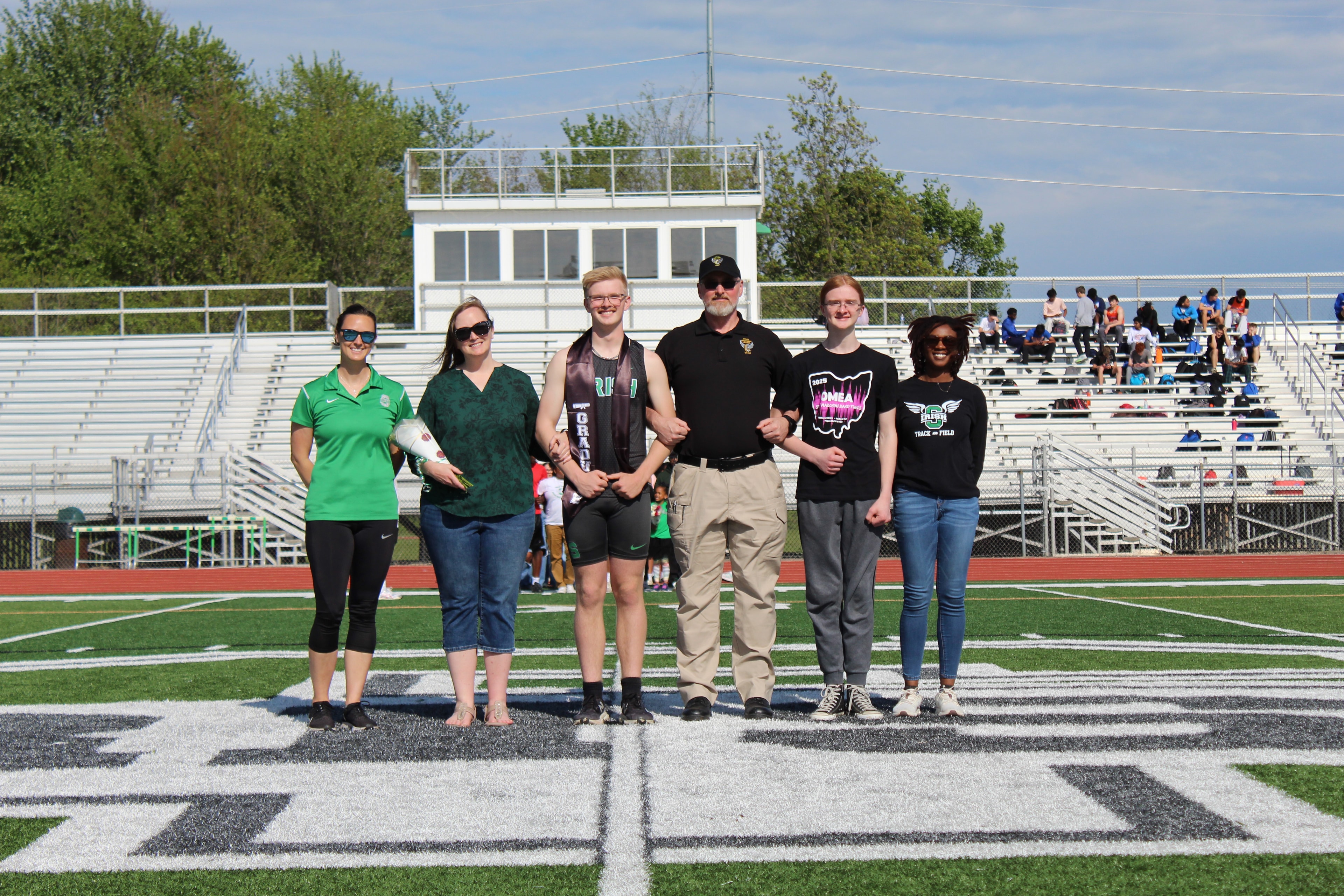 Senior in Irish jersey with large family group on the field