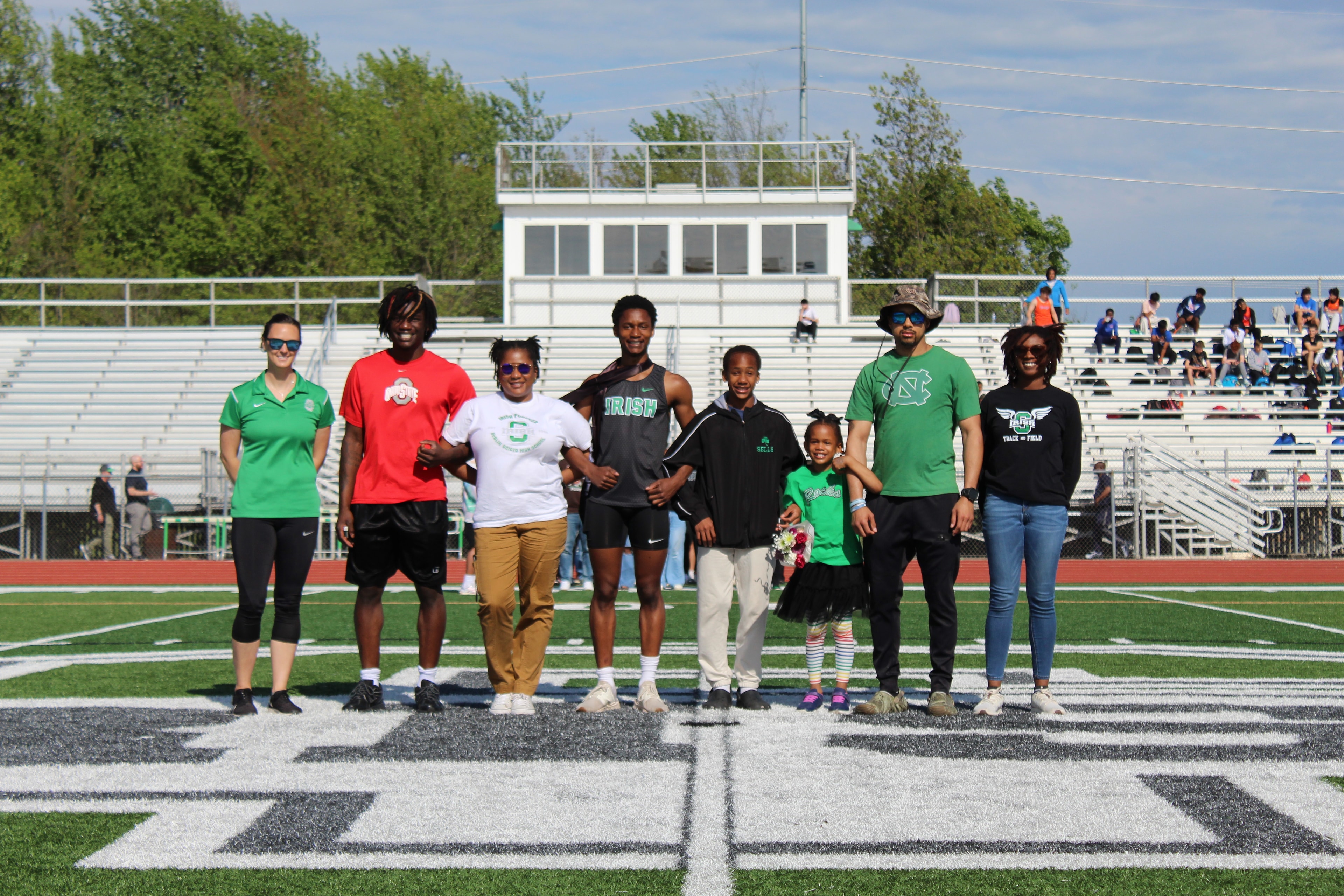 Senior with family and large group on the field during Senior Night