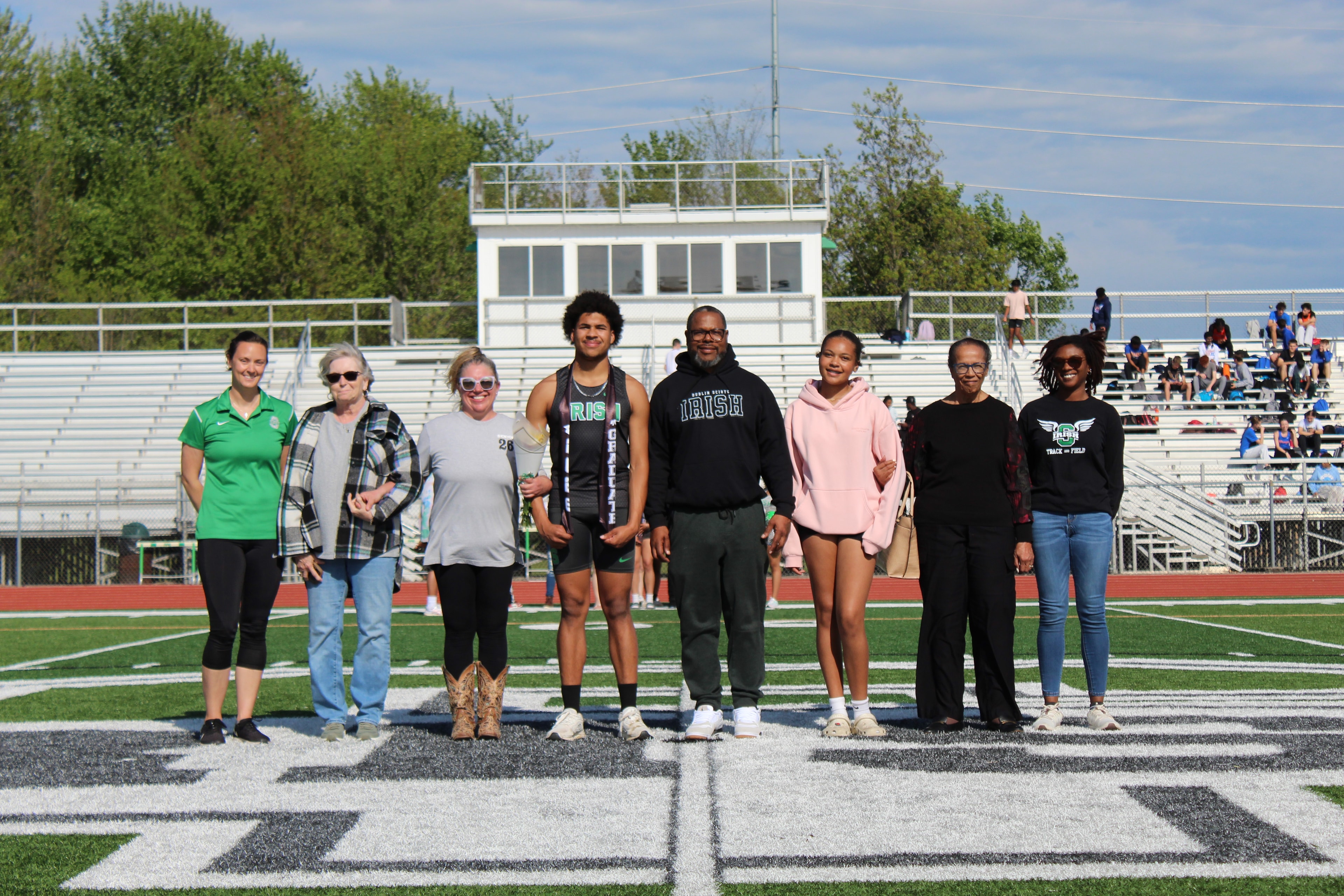 Senior in Irish jersey with family on the field