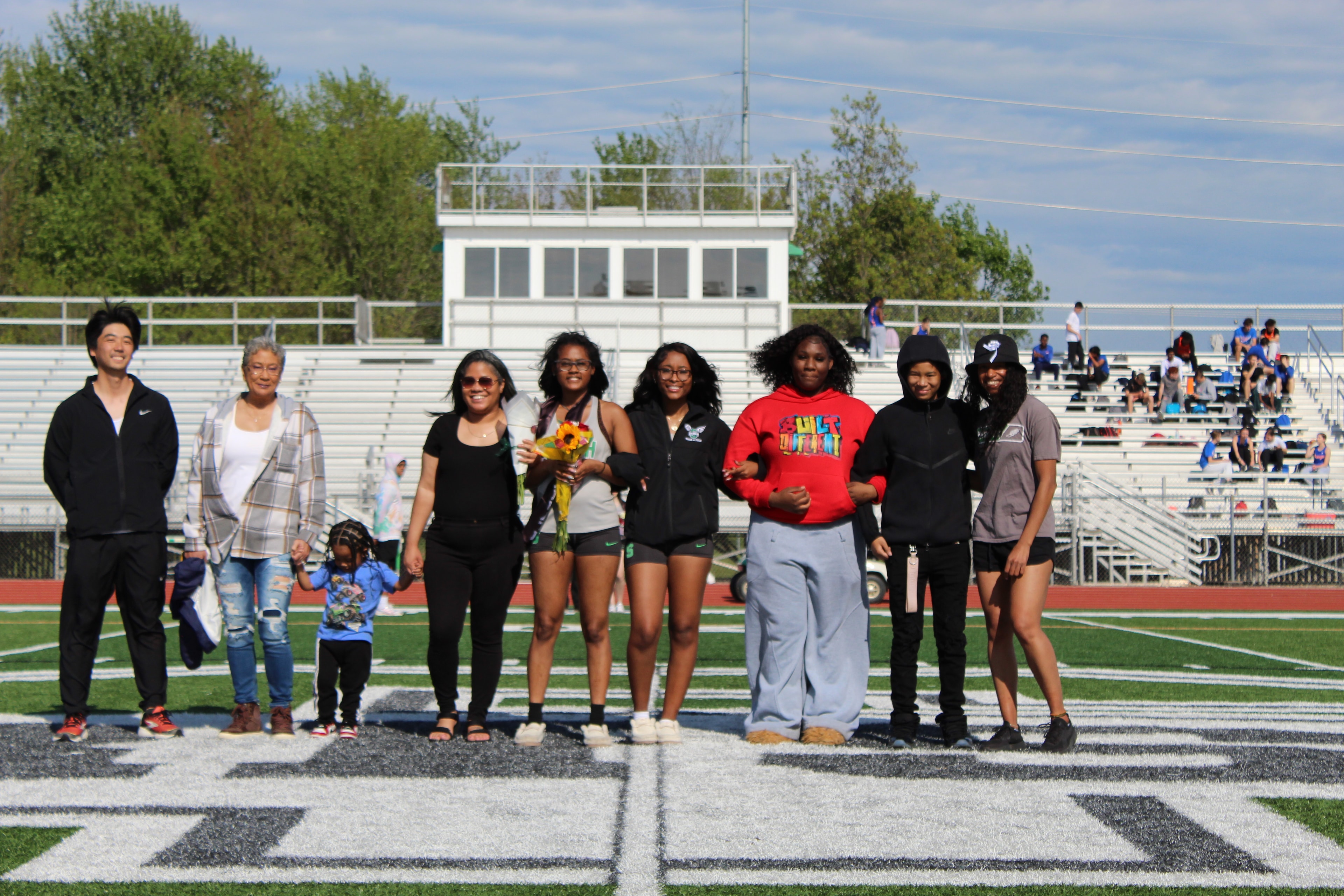 Senior with family and teammates on the field during Senior Night