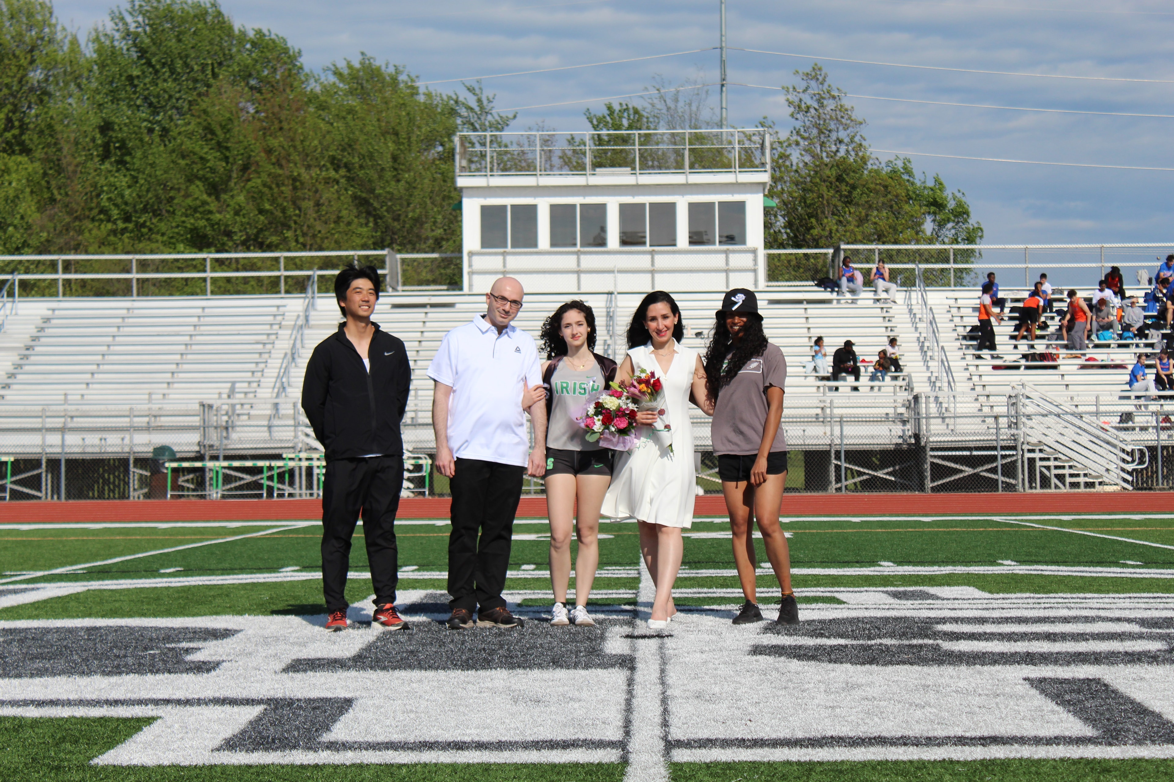 Senior in Irish jersey with family on the field during Senior Night