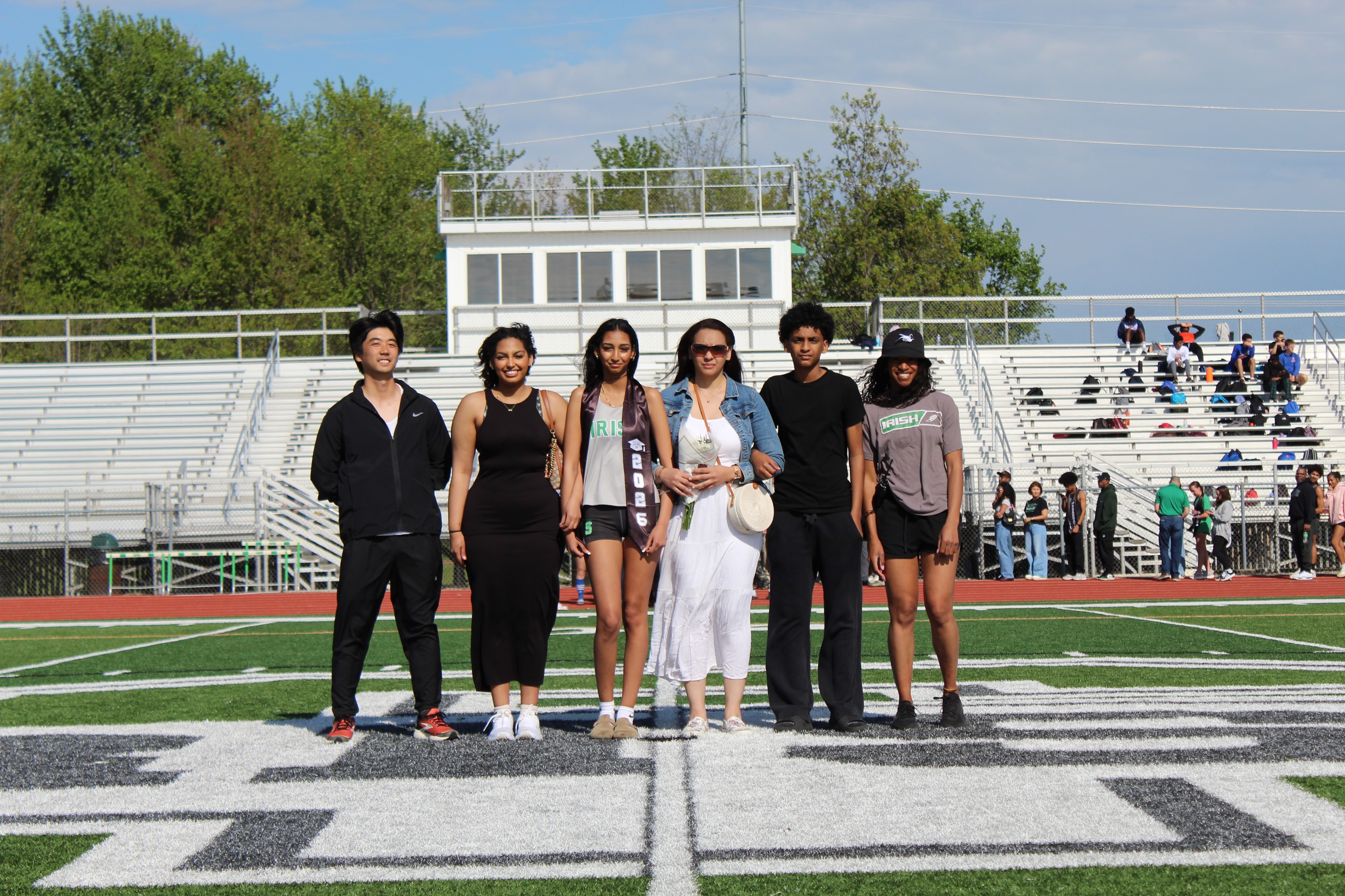Senior with graduation sash and family on the field