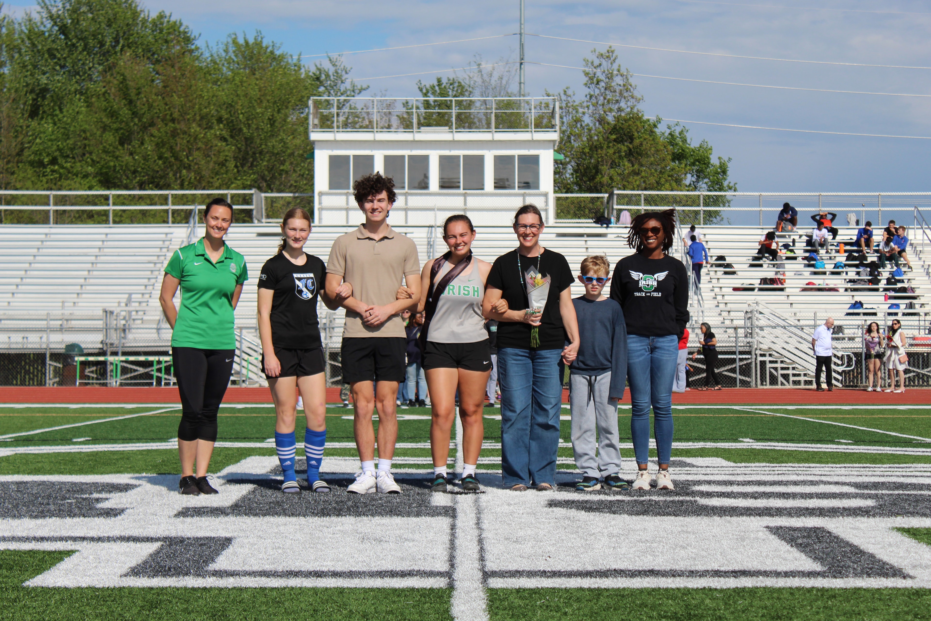 Senior athlete with family and coaches on the field