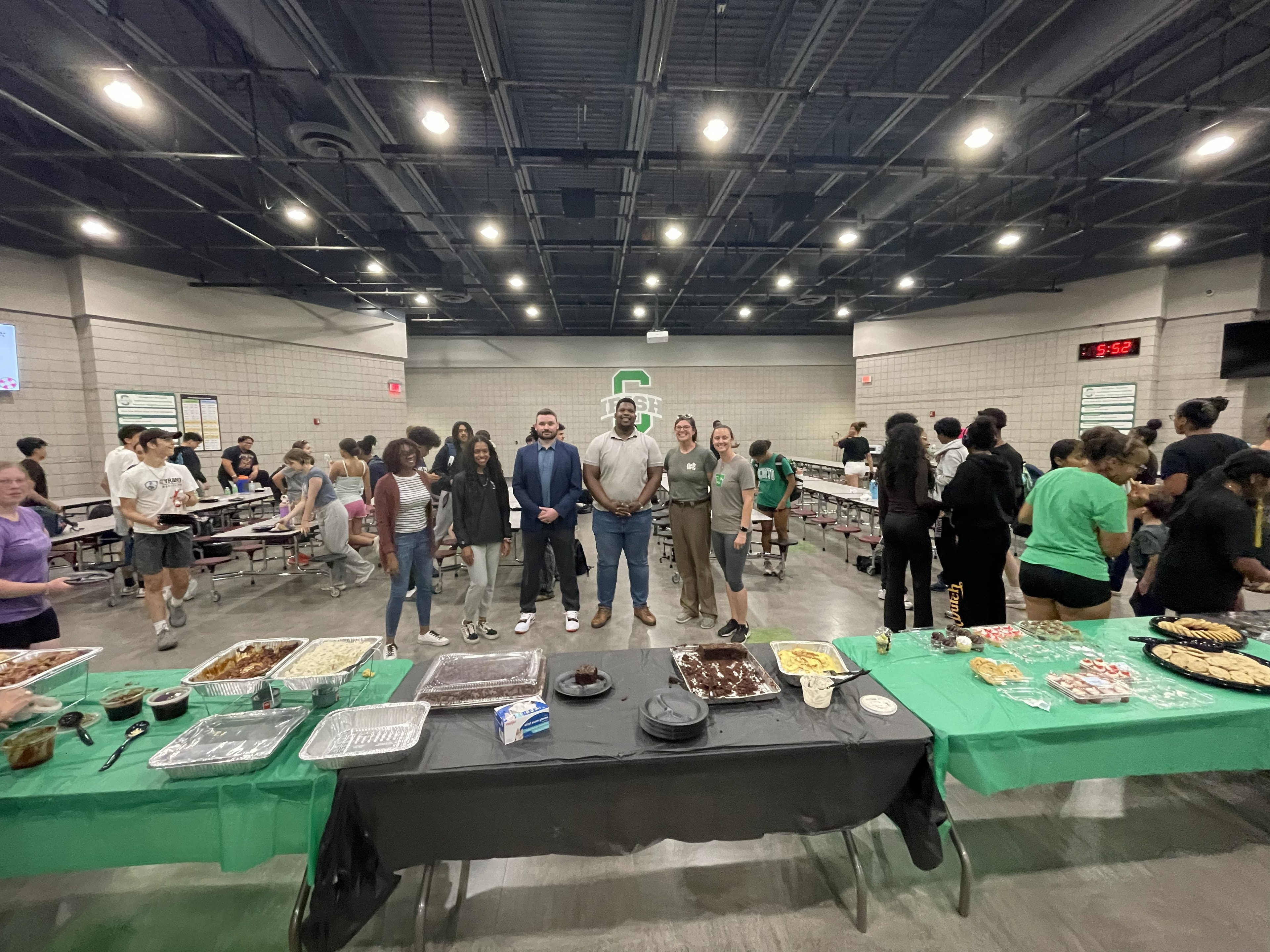 Coaches and staff posing in front of the food table